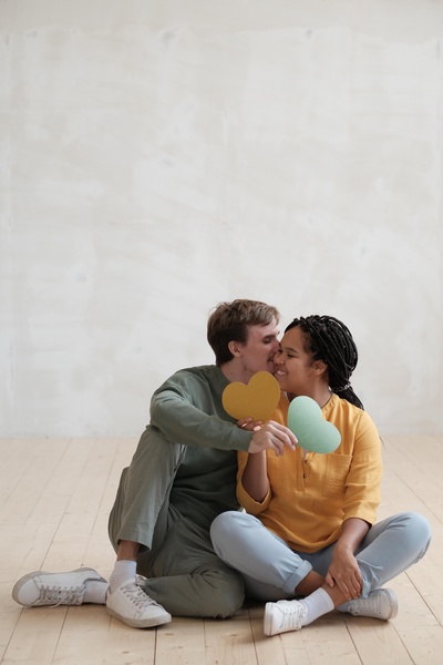 Man Kisses Sitting Woman Cheek
